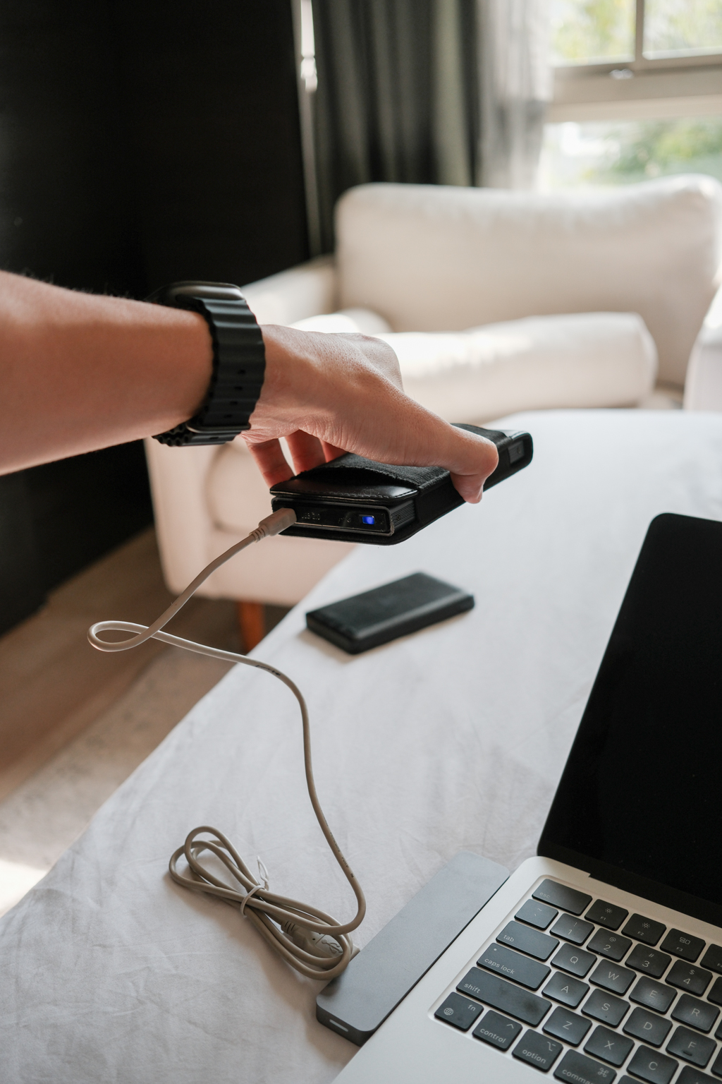 A hand holding a hard drive, over a bedsheet.